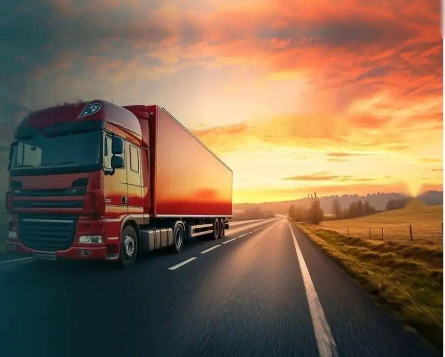 Red freight truck on an open road at sunset
